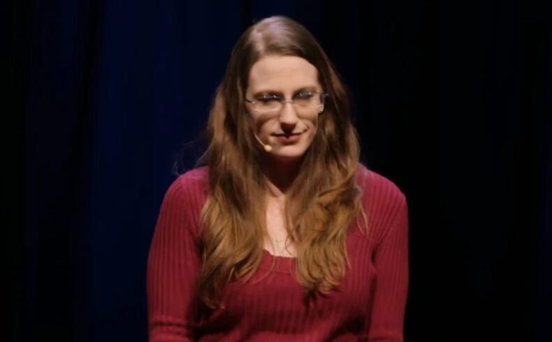 כריסטין רייטר עומדת על במת © TED ונושאת הרצאה אישית על הבחירה שלא להביא ילדים ועל לחץ חברתי סביב אימהות.