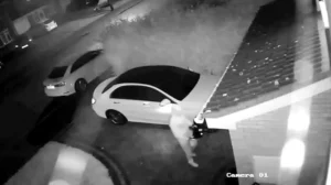 צילום ממצלמת אבטחה של גנב רכב משתמש בטאבלט ובמכשיר אלקטרוני כדי לפרוץ לרכב בחניה פרטית בשיטת Relay Attack