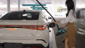 אישה מחברת רכב חשמלי של BYD לעמדת טעינה ציבורית – טעינת רכב חשמלי ושמירה על סוללה