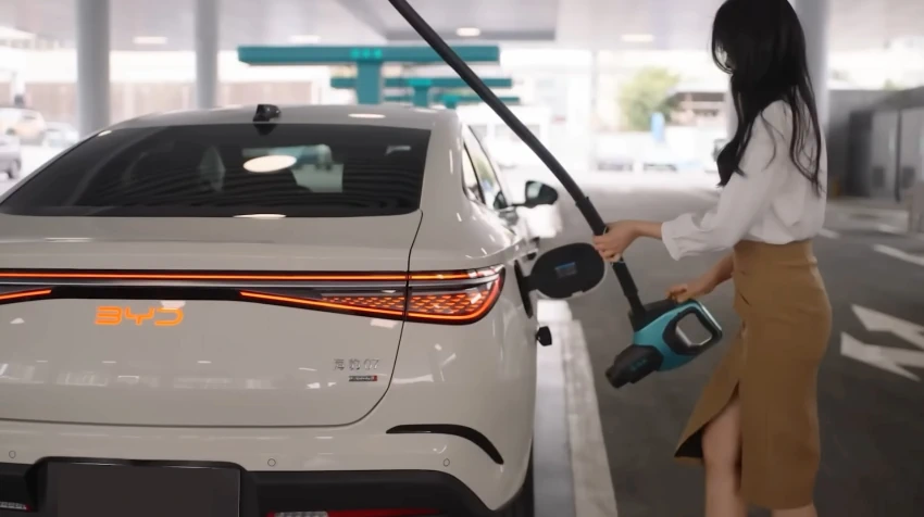 אישה מחברת רכב חשמלי של BYD לעמדת טעינה ציבורית – טעינת רכב חשמלי ושמירה על סוללה